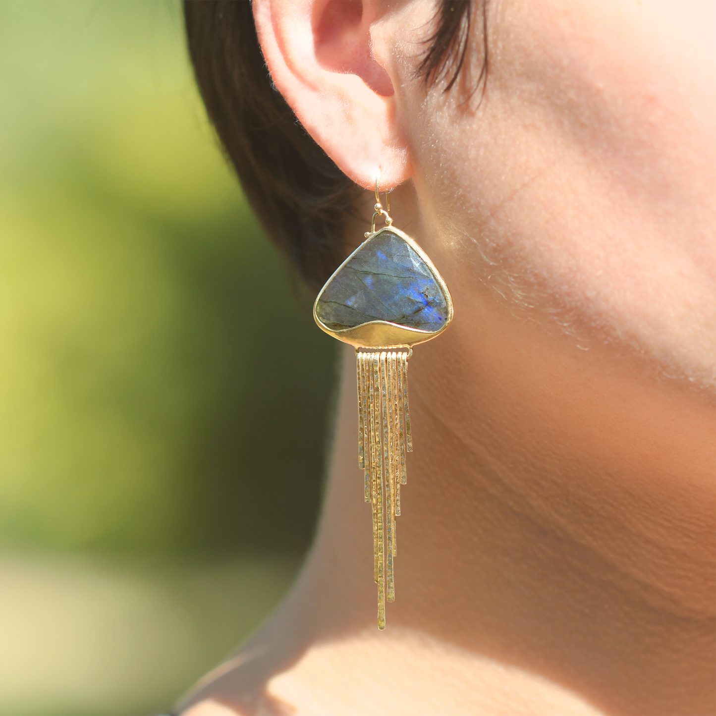 Dangle earrings in blue and grey faceted labradorite and 18k yellow gold. Bezel set, triangle-shaped stone, narrow hammered gold dangling elements, and french hooks.