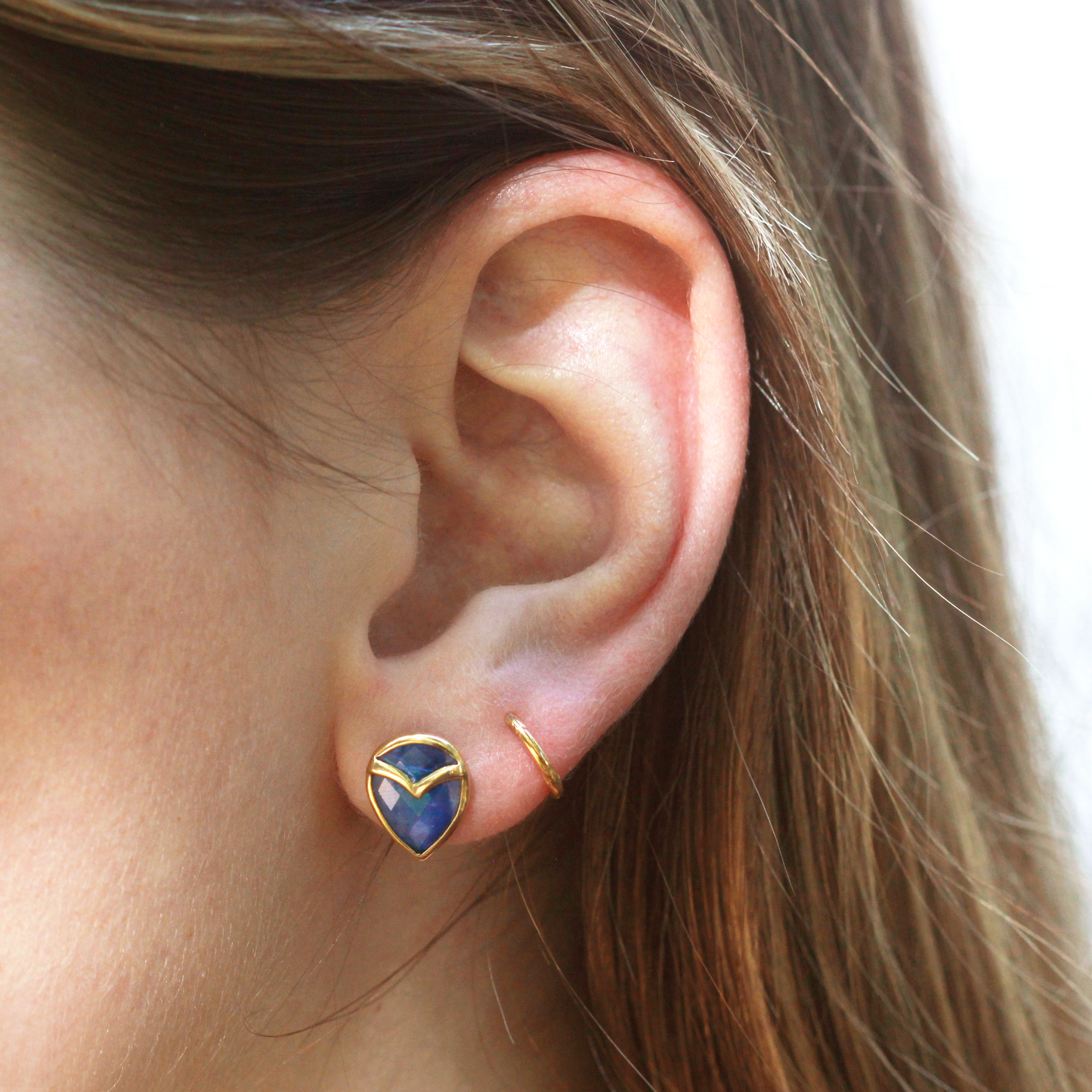 Woman wearing stud earring with teardrop-shaped, Blue Kyanite, bezel set with yellow gold owl beak detail