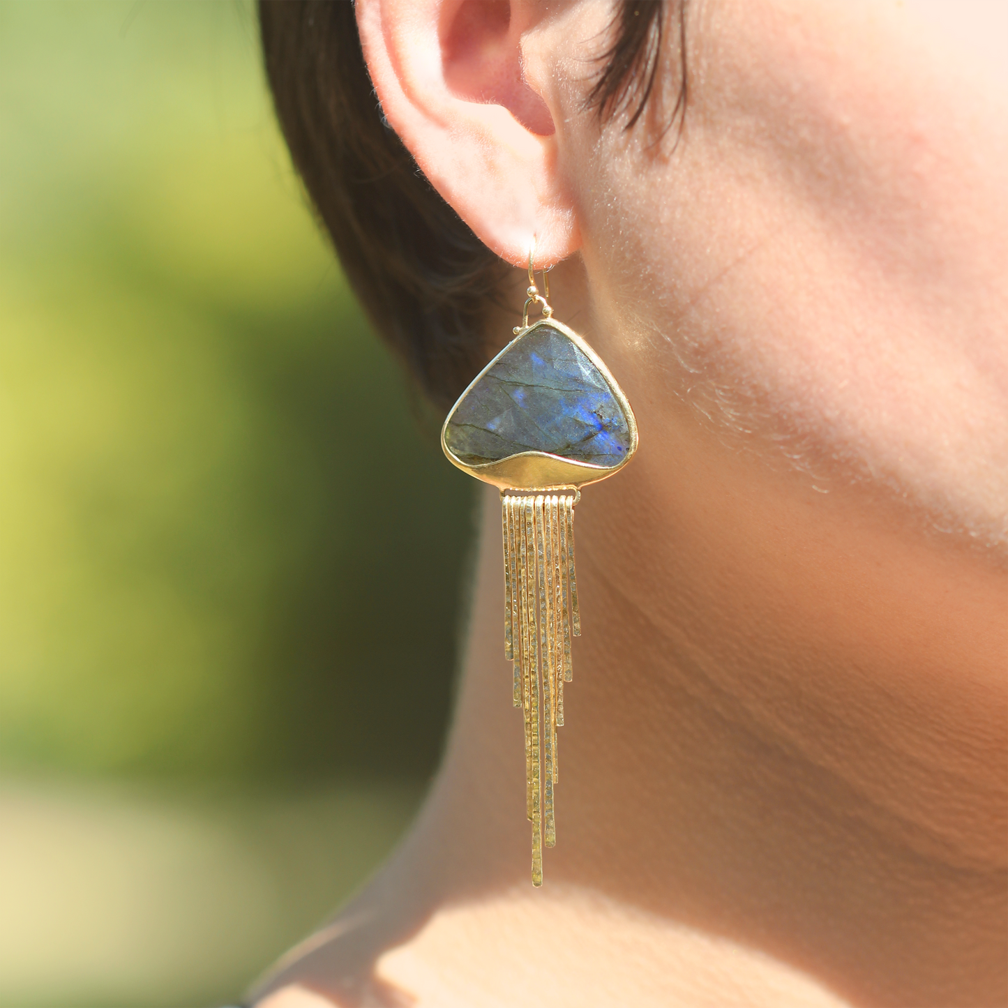 
                  
                    Dangle earrings in blue and grey faceted labradorite and 18k yellow gold. Bezel set, triangle-shaped stone, narrow hammered gold dangling elements, and french hooks.
                  
                
