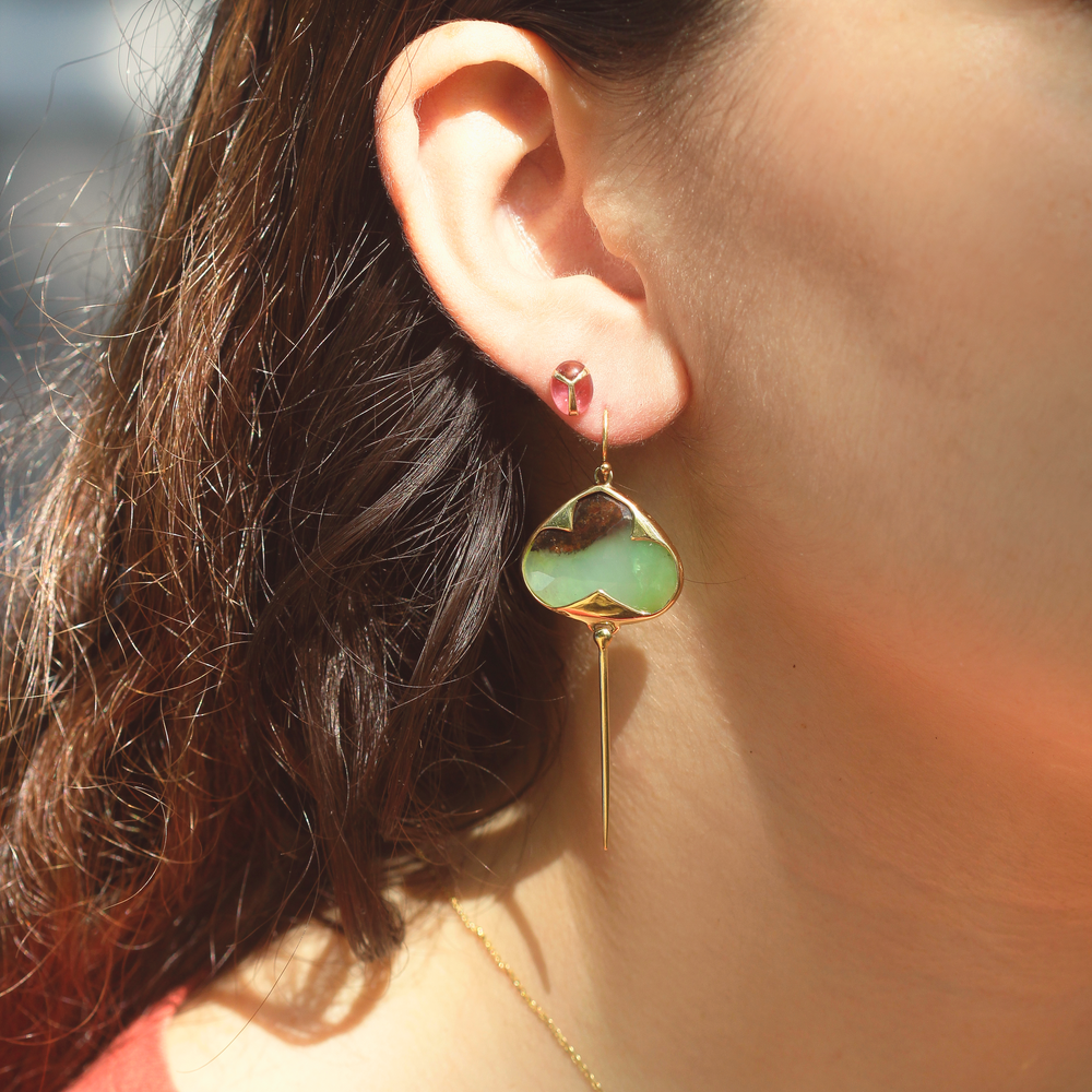 Woman modeling Yellow gold earrings with french hooks, bezel set green and black garnet stones, and an elongated tail dangling from the bottom