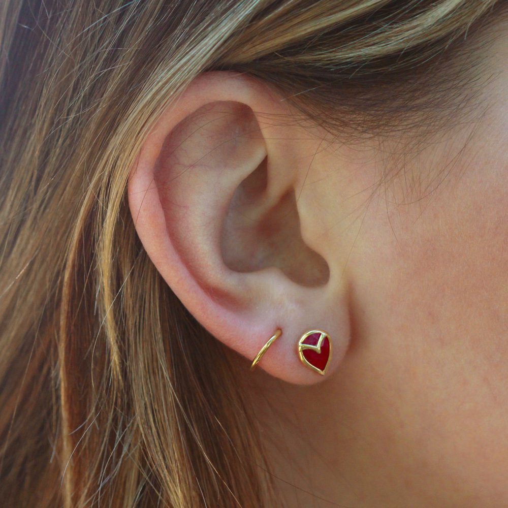 A pair of stud earrings with teardrop-shaped, dark pink rubies, bezel set with yellow gold owl beak detail