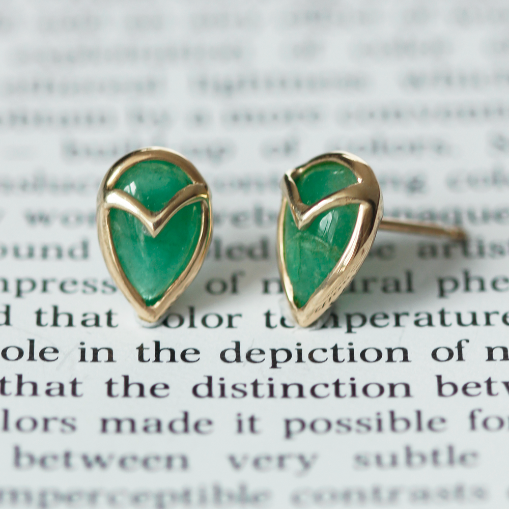 
                  
                    A pair of stud earrings with teardrop-shaped, green emerald stone, bezel set with yellow gold owl beak detail
                  
                